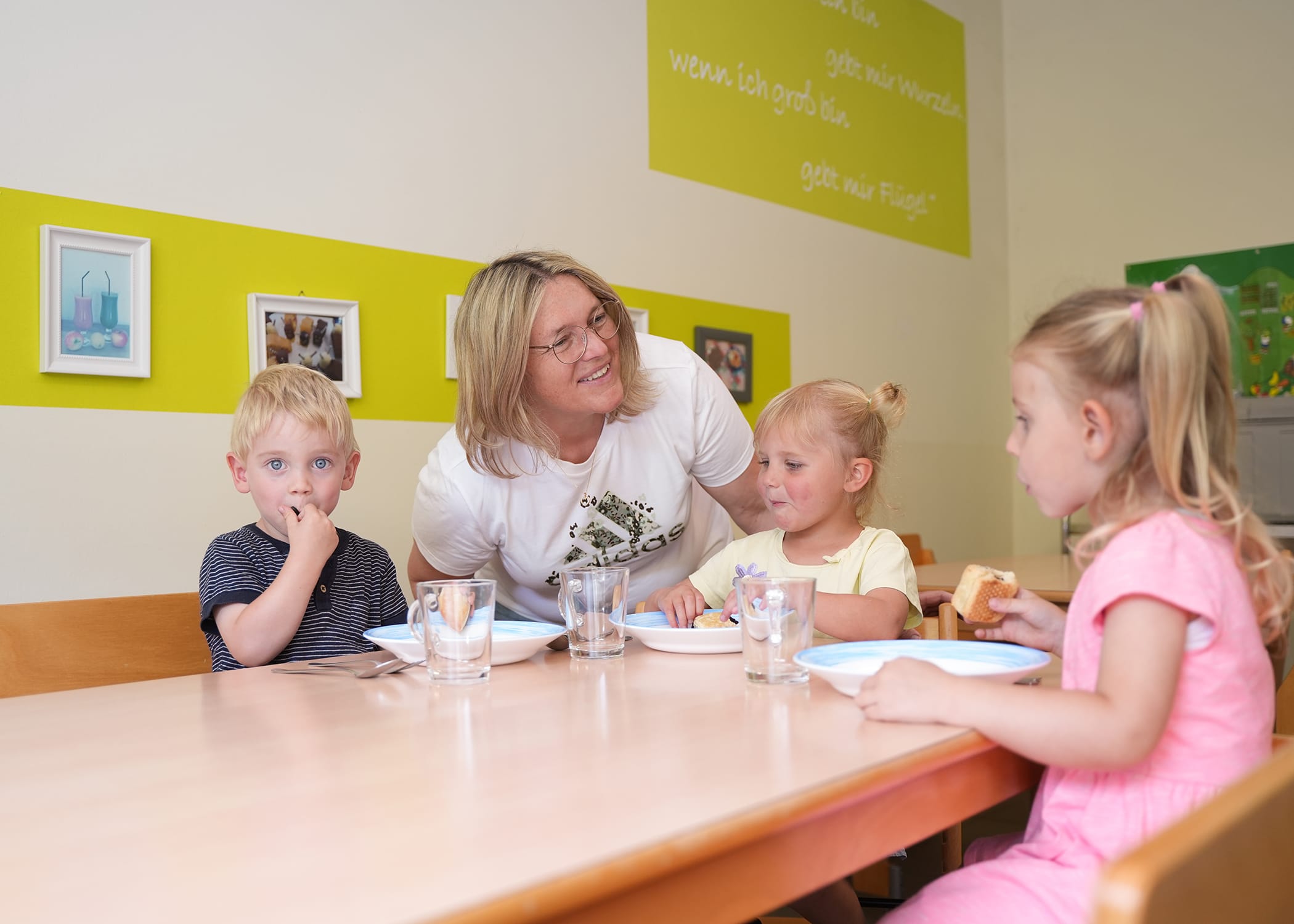 Raumbilder (15) Erzieherin mit drei Kindern am Tisch beim Essen