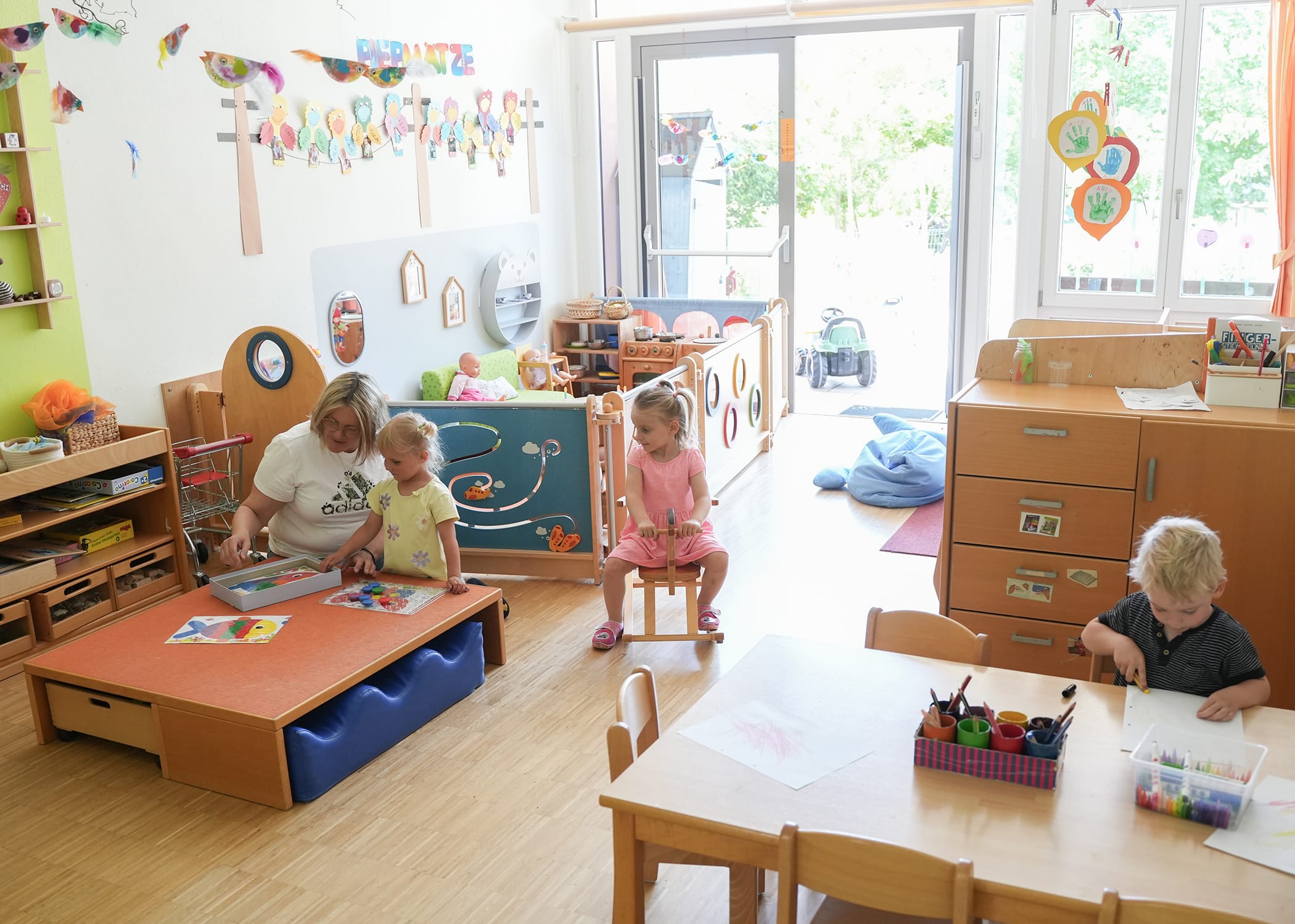 Raumbilder (38) Drei Kinder und Erzieherin beschäftigen sich im Krippenraum